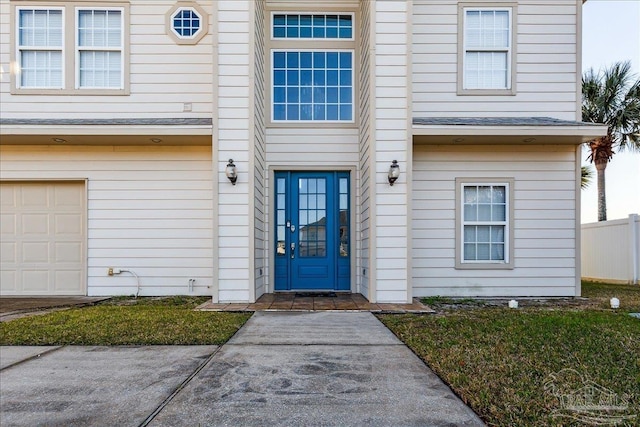 entrance to property with a garage and a lawn