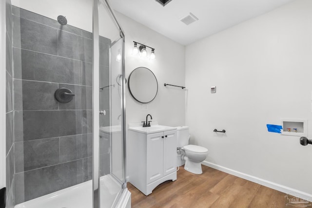 bathroom featuring hardwood / wood-style floors, vanity, a shower with shower door, and toilet