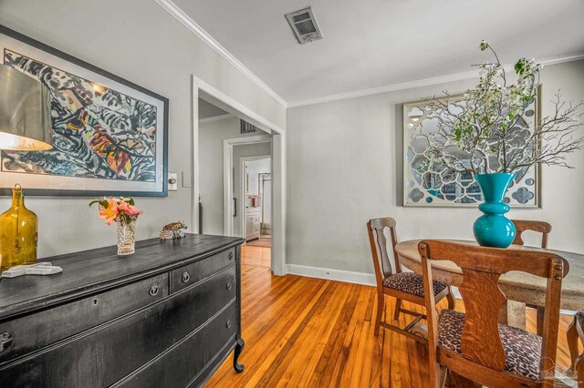 dining area featuring baseboards, visible vents, crown molding, and wood finished floors