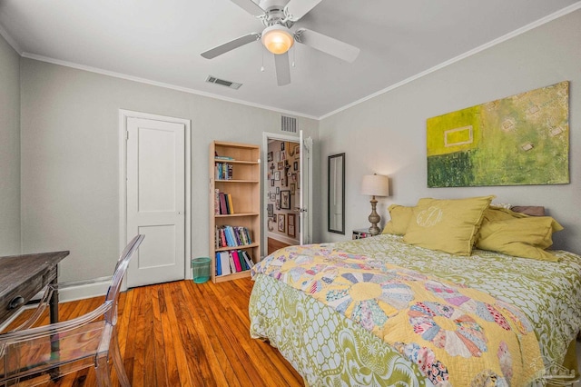 bedroom featuring visible vents, wood finished floors, and ornamental molding