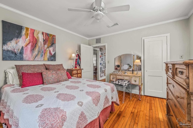 bedroom featuring ceiling fan, visible vents, crown molding, and wood finished floors