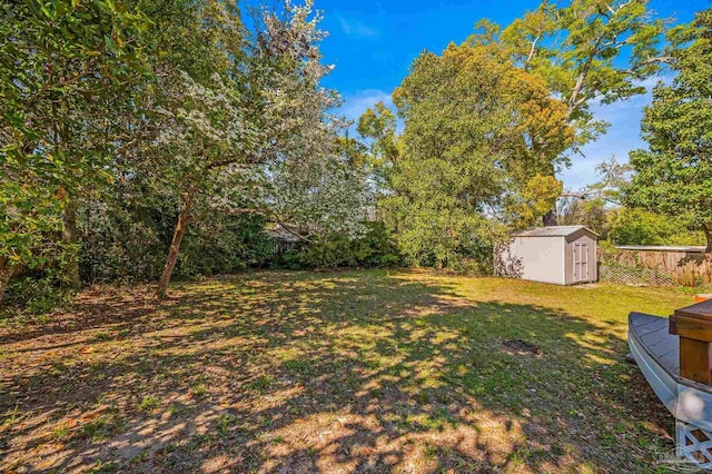 view of yard with an outdoor structure, fence, and a storage shed