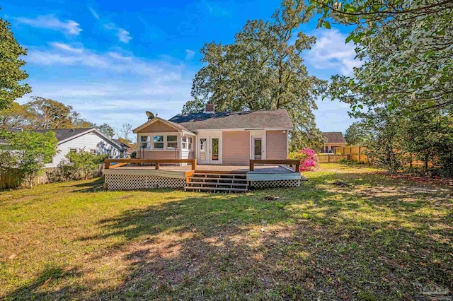 rear view of property featuring a wooden deck, a chimney, fence, and a lawn