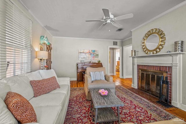 living room with ceiling fan, visible vents, crown molding, and wood finished floors
