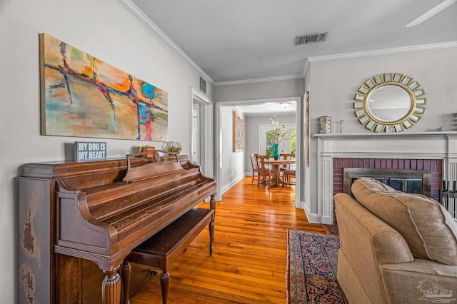sitting room with wood finished floors, ornamental molding, baseboards, and visible vents