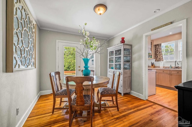 dining space featuring light wood-style flooring, ornamental molding, and baseboards