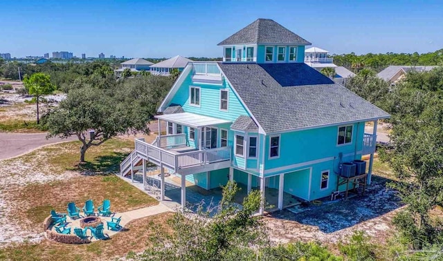 back of house with a fire pit, a garage, and a deck