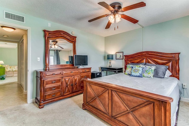 bedroom featuring baseboards, visible vents, light colored carpet, ceiling fan, and a textured ceiling