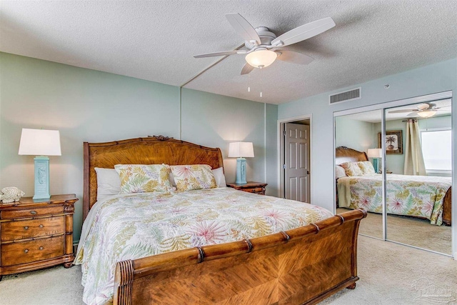 bedroom featuring a textured ceiling, a closet, visible vents, and light colored carpet