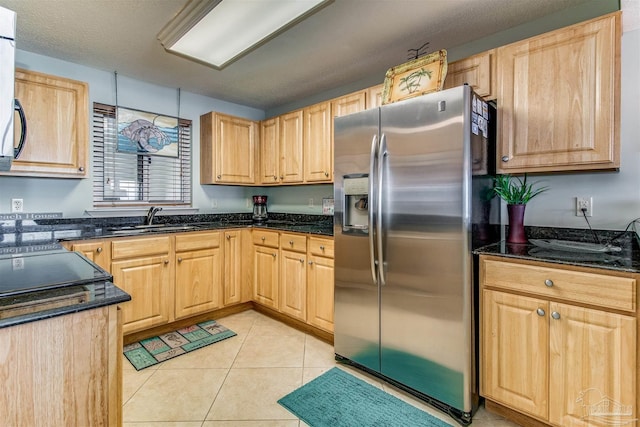 kitchen featuring a sink, light brown cabinetry, light tile patterned flooring, and stainless steel fridge