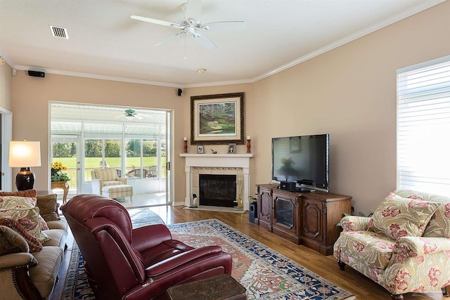 1424 Champions Green Dr, Gulf Breeze, FL 32563 - living room with a tiled fireplace, ornamental molding, ceiling fan, and wood finished floors