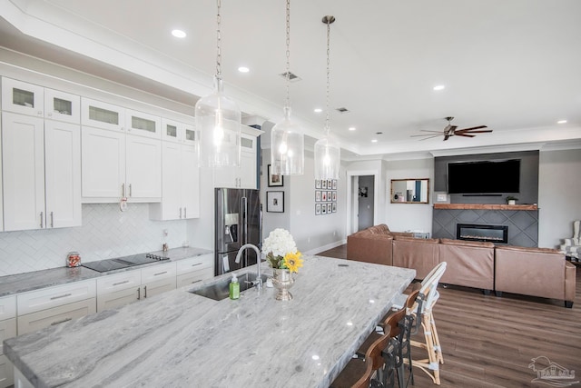 kitchen featuring sink, stainless steel refrigerator with ice dispenser, light stone countertops, dark hardwood / wood-style flooring, and white cabinetry