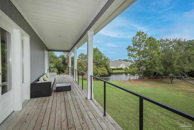 deck with outdoor lounge area, a yard, and a water view