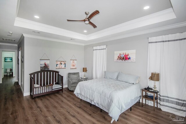 bedroom featuring a tray ceiling, ceiling fan, dark wood-type flooring, and ornamental molding