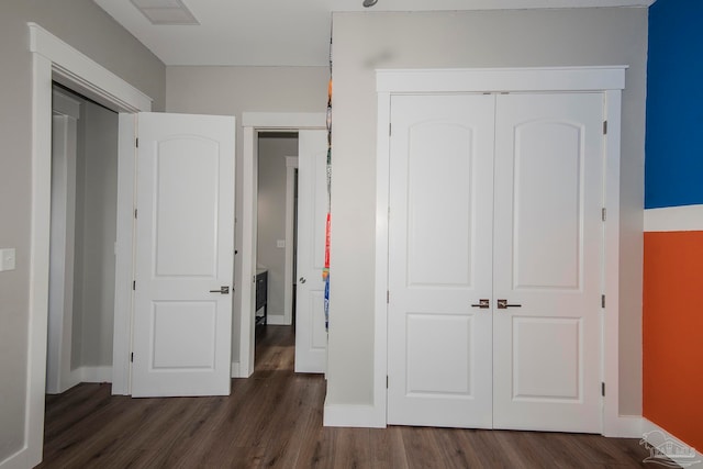 unfurnished bedroom featuring a closet and dark wood-type flooring