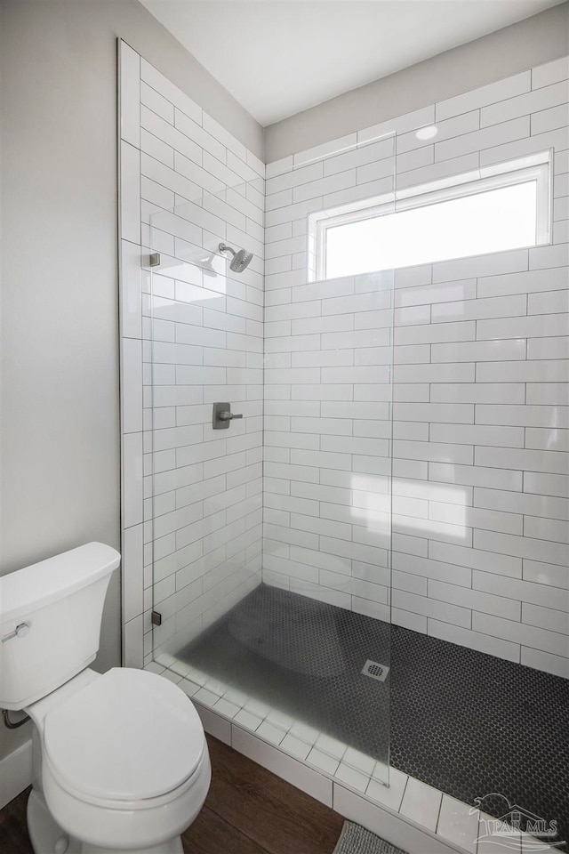 bathroom featuring tiled shower, toilet, and hardwood / wood-style flooring