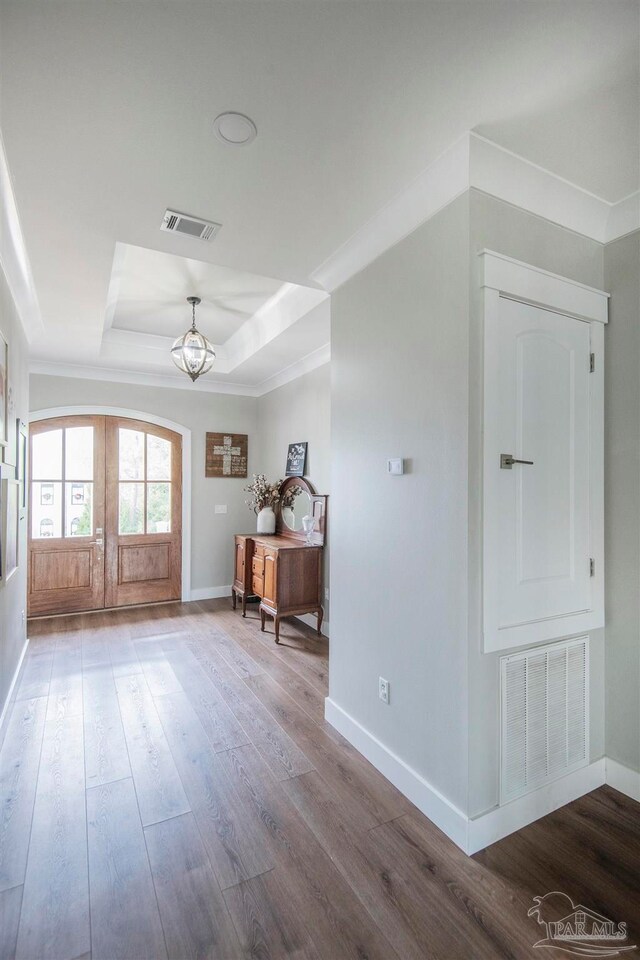 interior space featuring french doors, an inviting chandelier, hardwood / wood-style flooring, and a raised ceiling