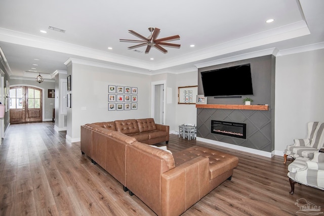 living room with ceiling fan, french doors, crown molding, a tray ceiling, and light wood-type flooring