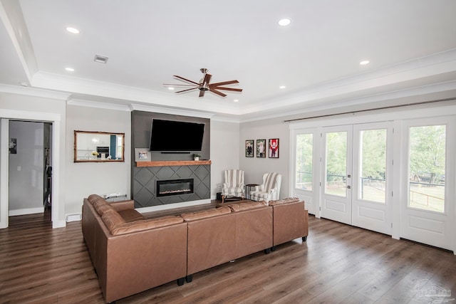 living room featuring dark hardwood / wood-style floors, ceiling fan, crown molding, and a tray ceiling