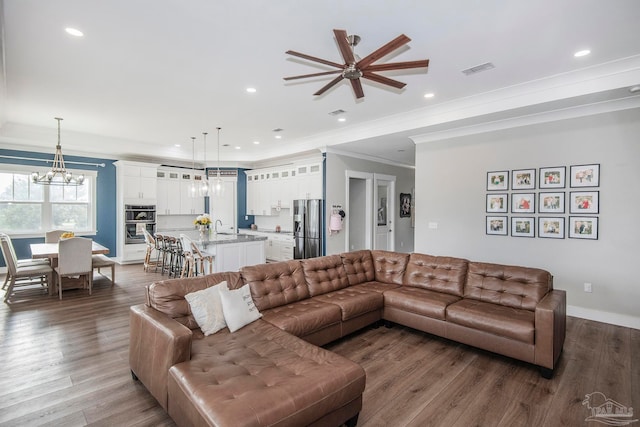 living room with ceiling fan with notable chandelier, dark hardwood / wood-style flooring, ornamental molding, and sink