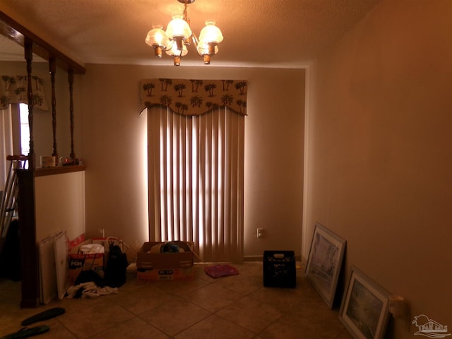 unfurnished dining area with an inviting chandelier, tile patterned flooring, and a textured ceiling