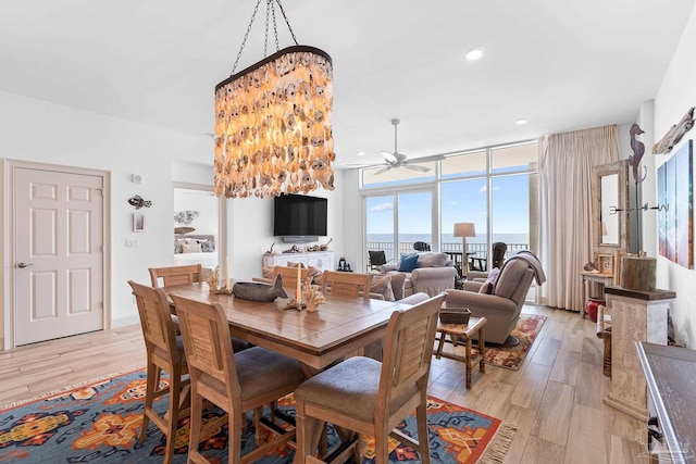 dining room with a wall of windows, ceiling fan, and light wood-type flooring