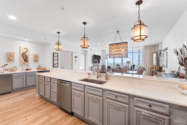 kitchen featuring gray cabinets, dishwasher, light hardwood / wood-style floors, and decorative light fixtures