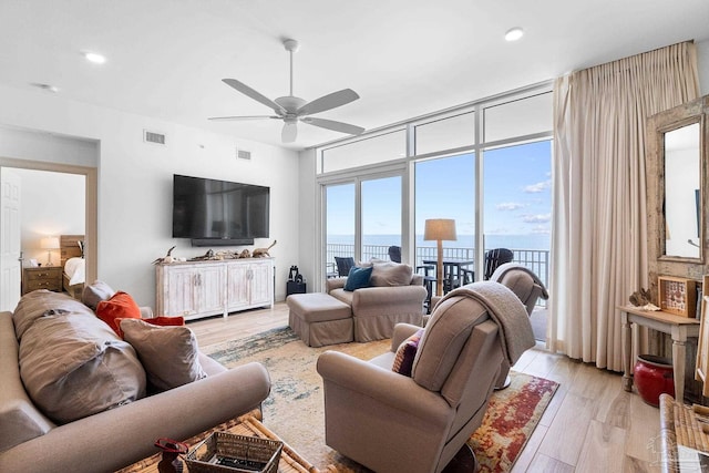 living room with ceiling fan, floor to ceiling windows, and light wood-type flooring