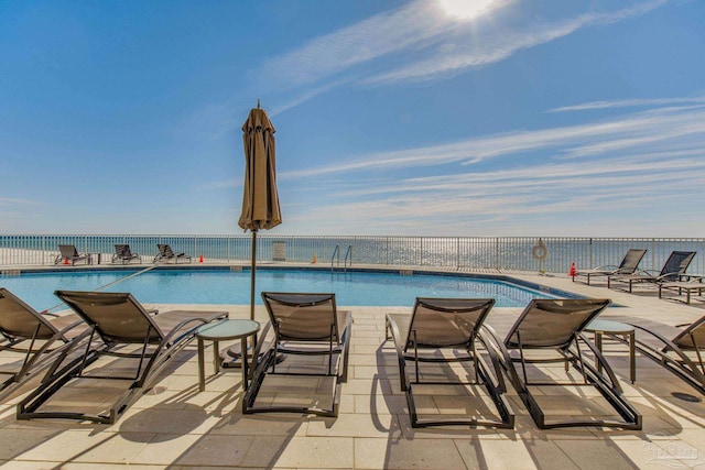 view of swimming pool featuring a water view and a patio