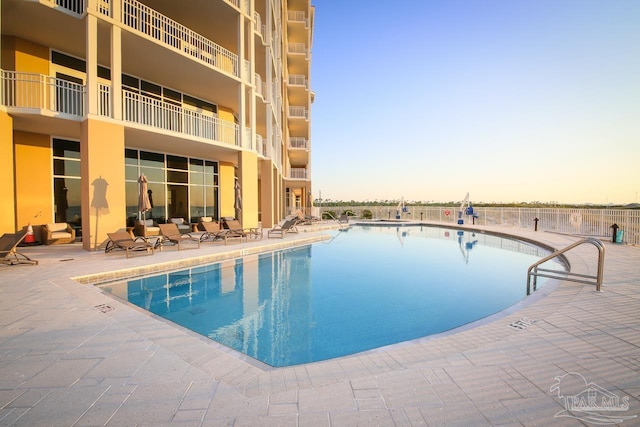 pool at dusk with a patio area