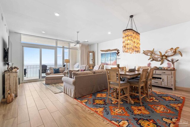 dining space featuring ceiling fan with notable chandelier, light hardwood / wood-style floors, and expansive windows