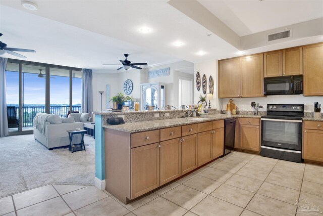 kitchen with kitchen peninsula, light colored carpet, a wall of windows, and black appliances