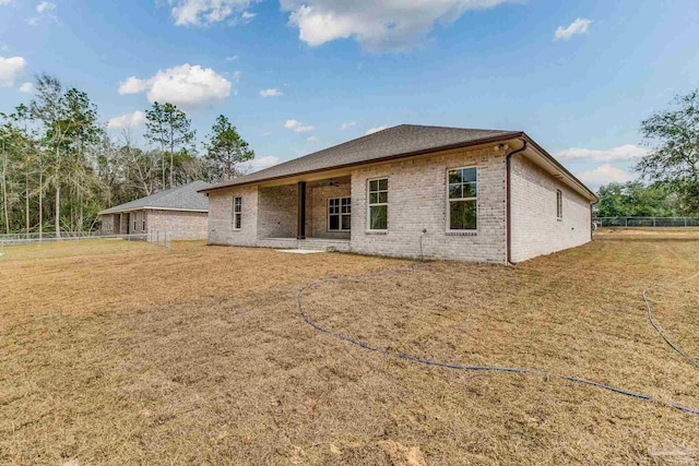 rear view of property with a yard, ceiling fan, fence, and brick siding