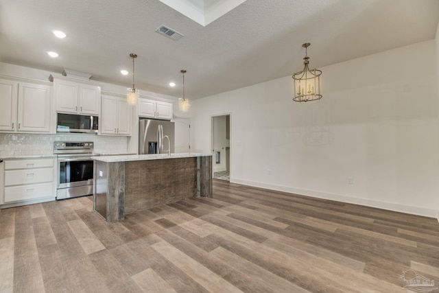 kitchen with stainless steel appliances, tasteful backsplash, light countertops, visible vents, and light wood-type flooring