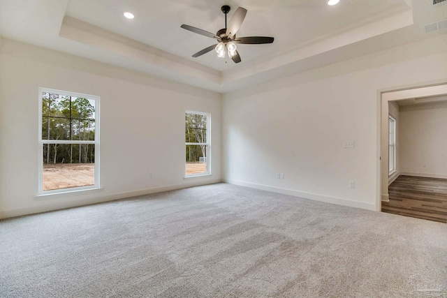 carpeted empty room featuring ceiling fan, recessed lighting, visible vents, baseboards, and a raised ceiling