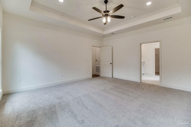 unfurnished bedroom with light carpet, visible vents, baseboards, ornamental molding, and a tray ceiling