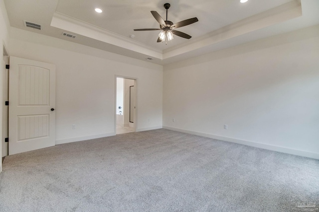 spare room with carpet, a raised ceiling, visible vents, and crown molding