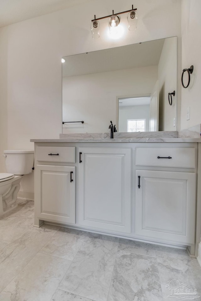 bathroom featuring toilet, marble finish floor, and vanity