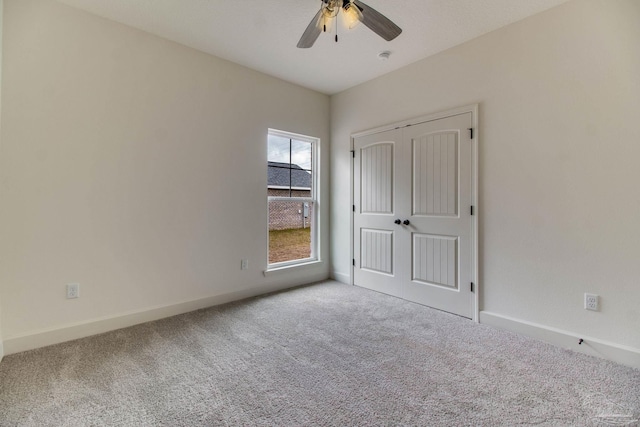 unfurnished bedroom with carpet, baseboards, ceiling fan, and a closet