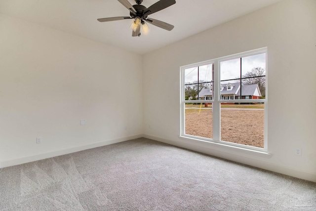 carpeted empty room with a ceiling fan and baseboards