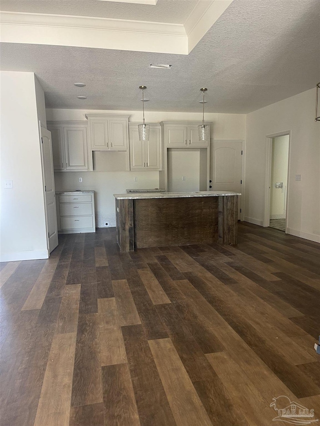 kitchen featuring baseboards, a kitchen island, dark wood-type flooring, hanging light fixtures, and a textured ceiling