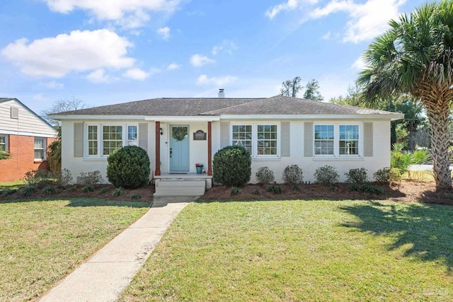 ranch-style house featuring roof with shingles, a front yard, and brick siding