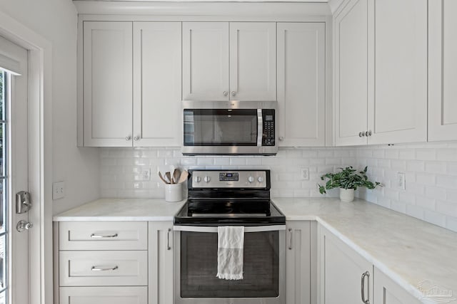 kitchen featuring appliances with stainless steel finishes, white cabinets, light countertops, and backsplash