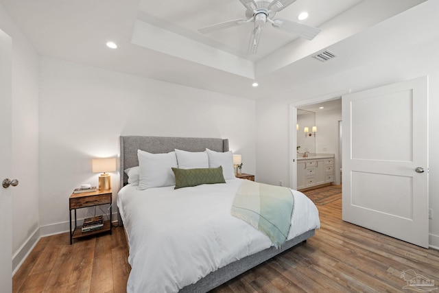 bedroom featuring baseboards, visible vents, wood finished floors, a tray ceiling, and recessed lighting