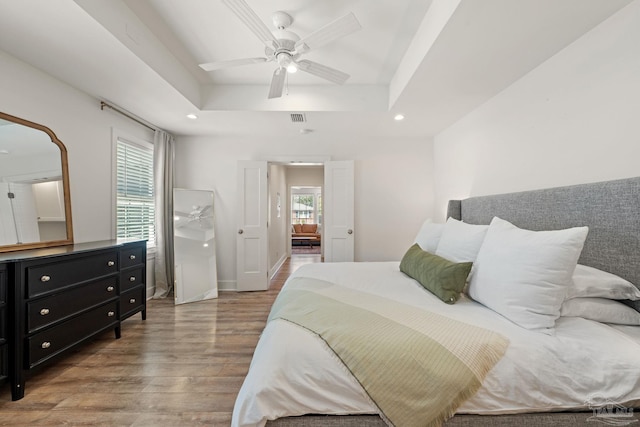 bedroom with visible vents, a raised ceiling, baseboards, light wood-style flooring, and recessed lighting