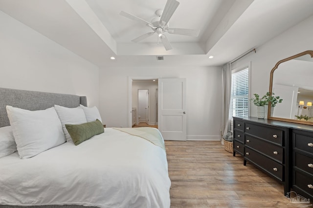 bedroom with ceiling fan, recessed lighting, visible vents, light wood-type flooring, and a raised ceiling