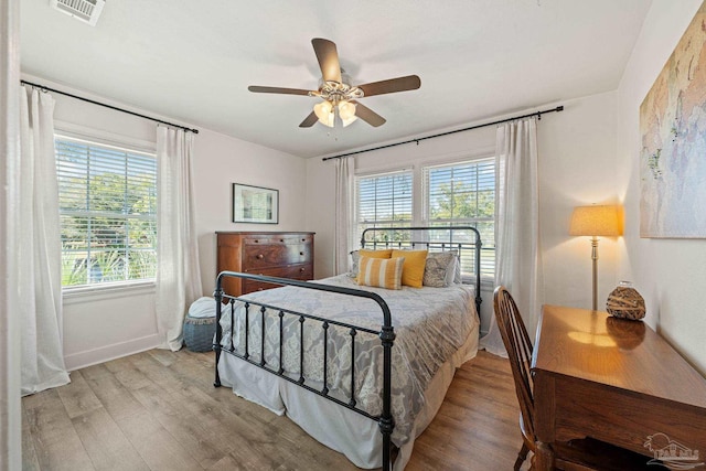 bedroom featuring ceiling fan, light wood-style flooring, visible vents, and baseboards