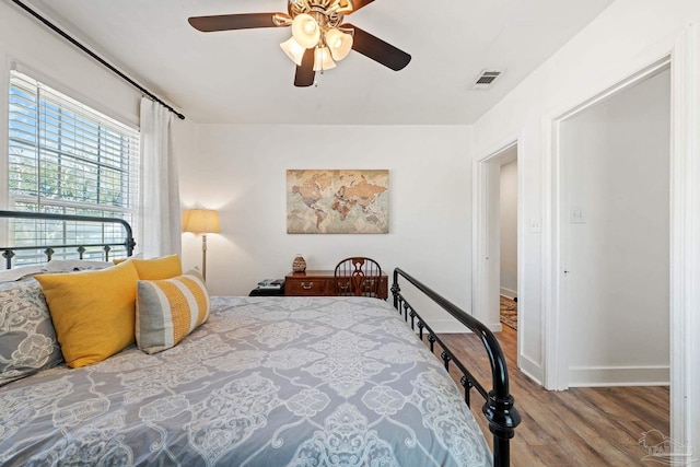 bedroom with baseboards, wood finished floors, visible vents, and a ceiling fan