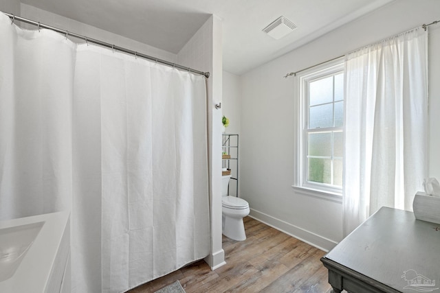 bathroom featuring toilet, wood finished floors, visible vents, and baseboards