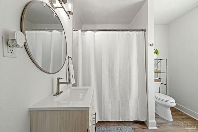 bathroom with toilet, wood finished floors, and vanity